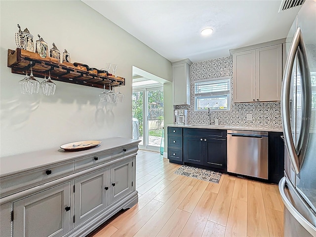 kitchen with appliances with stainless steel finishes, light countertops, a sink, gray cabinetry, and visible vents