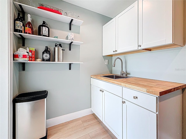laundry room featuring baseboards, light wood-style flooring, and a sink
