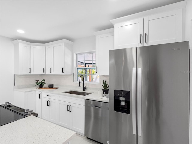 kitchen featuring a sink, backsplash, white cabinets, and appliances with stainless steel finishes