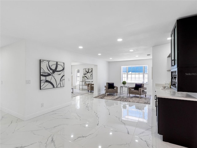 interior space featuring baseboards, open floor plan, light countertops, recessed lighting, and marble finish floor