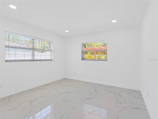 empty room featuring a wealth of natural light, recessed lighting, and baseboards