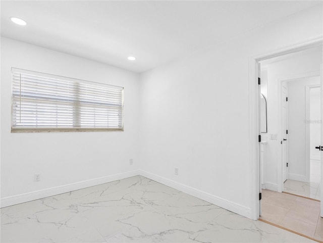 spare room featuring recessed lighting, marble finish floor, and baseboards