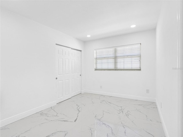 unfurnished bedroom featuring a closet, baseboards, recessed lighting, and marble finish floor