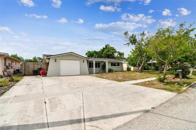 ranch-style home with a garage, fence, stucco siding, and concrete driveway