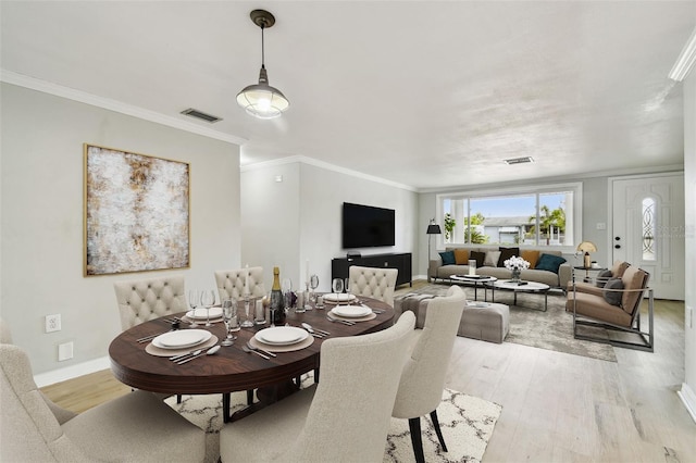 dining room with crown molding, baseboards, light wood-type flooring, and visible vents
