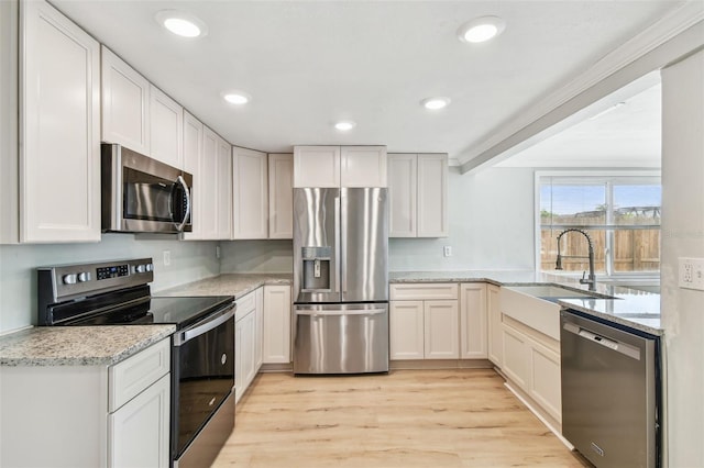 kitchen with light stone countertops, a sink, stainless steel appliances, recessed lighting, and light wood-type flooring