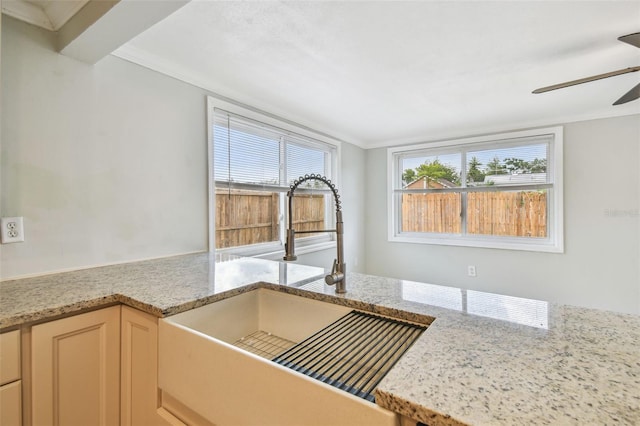 interior details featuring light stone counters, a sink, and ceiling fan