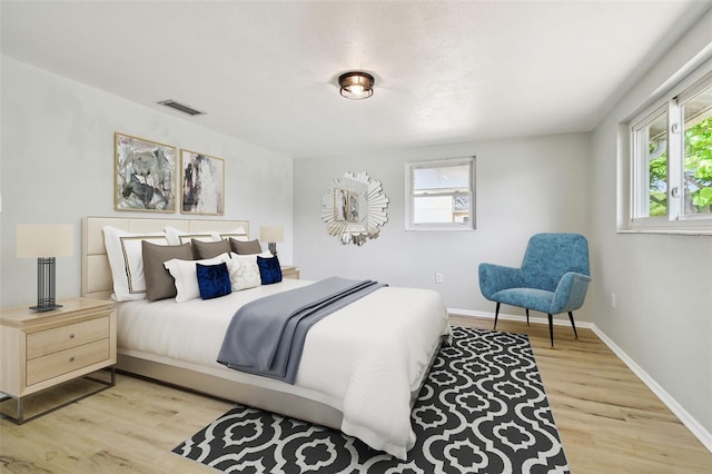 bedroom featuring wood finished floors, baseboards, visible vents, and multiple windows