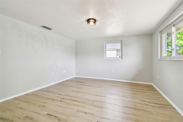 spare room featuring visible vents, a wealth of natural light, and light wood finished floors
