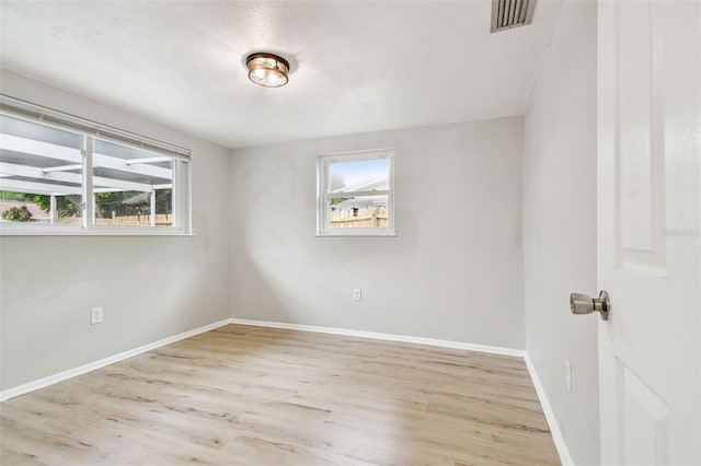 spare room featuring baseboards, wood finished floors, and visible vents
