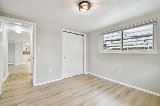 unfurnished bedroom featuring baseboards, a closet, and wood finished floors