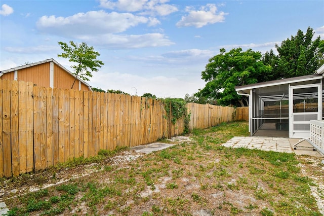 view of yard with a sunroom, a fenced backyard, and a patio