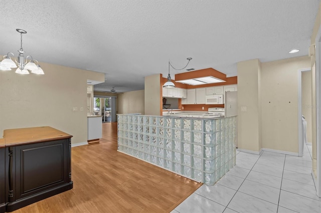 2023 Golfview Dr Unit 2023, Tarpon Springs, FL 34689 - kitchen with white appliances, baseboards, a chandelier, a textured ceiling, and hanging light fixtures