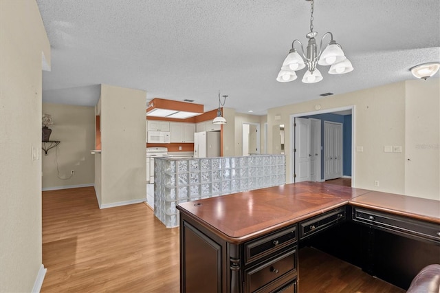 2023 Golfview Dr Unit 2023, Tarpon Springs, FL 34689 - kitchen featuring white appliances, a chandelier, a textured ceiling, light wood-style flooring, and baseboards