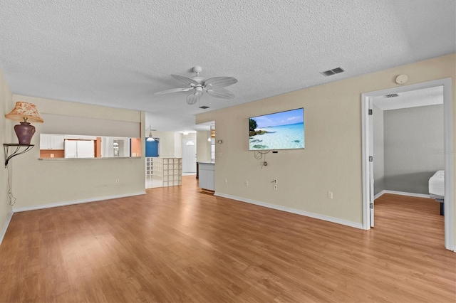 2023 Golfview Dr Unit 2023, Tarpon Springs, FL 34689 - unfurnished living room with ceiling fan, a textured ceiling, light wood finished floors, and baseboards