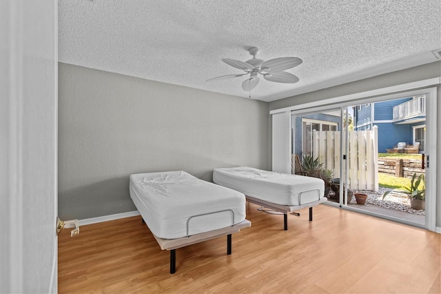 2023 Golfview Dr Unit 2023, Tarpon Springs, FL 34689 - bedroom with access to exterior, wood finished floors, a textured ceiling, and ceiling fan
