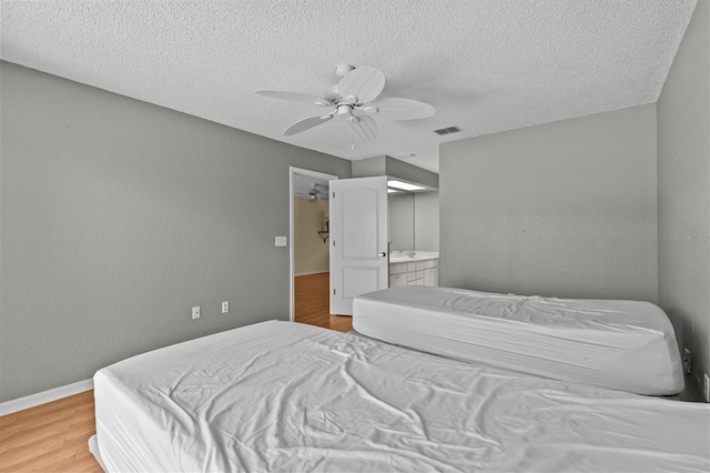 2023 Golfview Dr Unit 2023, Tarpon Springs, FL 34689 - bedroom featuring wood finished floors, a textured ceiling, a ceiling fan, baseboards, and ensuite bath