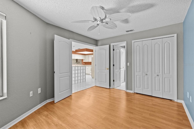 2023 Golfview Dr Unit 2023, Tarpon Springs, FL 34689 - unfurnished bedroom with wood finished floors, baseboards, a textured ceiling, ceiling fan, and freestanding refrigerator