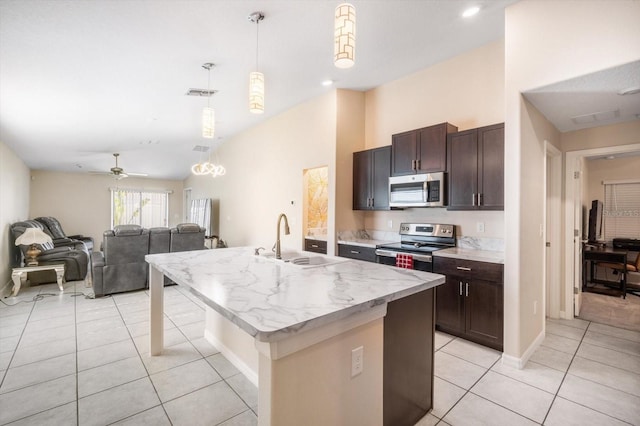 kitchen featuring light tile patterned floors, a sink, open floor plan, appliances with stainless steel finishes, and dark brown cabinetry