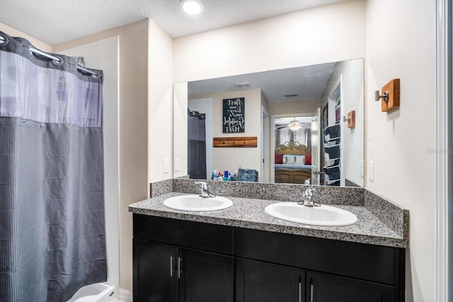 full bath featuring a sink, a shower with shower curtain, double vanity, and connected bathroom