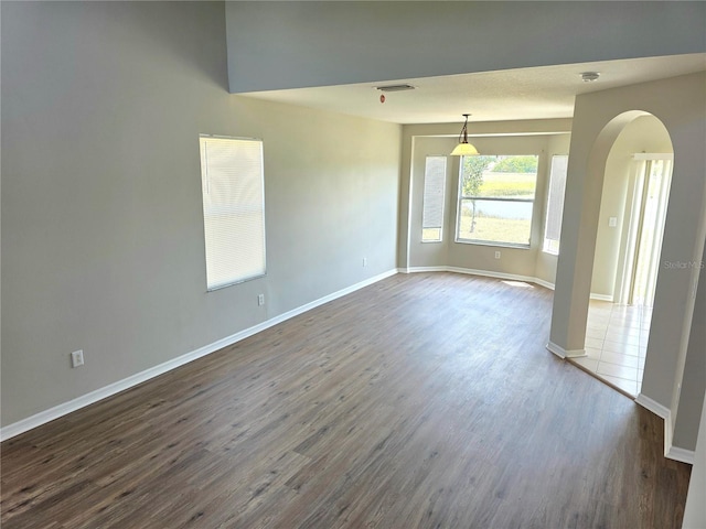 12604 Montford Ln, Riverview, FL 33579 - unfurnished room with arched walkways, dark wood-type flooring, visible vents, and baseboards