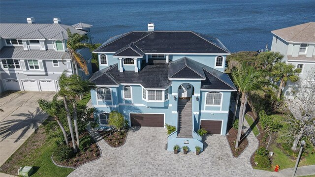 raised beach house with a balcony, a chimney, decorative driveway, stucco siding, and a garage