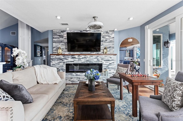 living area with a tile fireplace, arched walkways, and visible vents