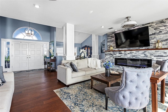 living room with a chandelier, vaulted ceiling, decorative columns, a fireplace, and wood finished floors