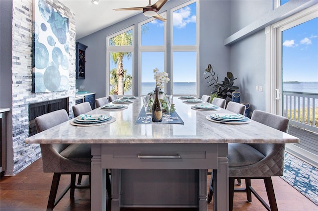 dining area with dark wood-style floors, ceiling fan, a water view, and vaulted ceiling