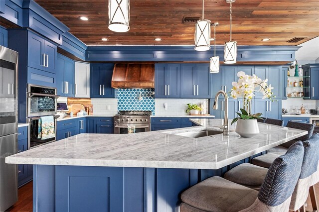 kitchen featuring appliances with stainless steel finishes, blue cabinetry, premium range hood, and wooden ceiling