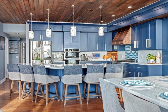 kitchen with blue cabinets, stainless steel double oven, custom range hood, and wood ceiling