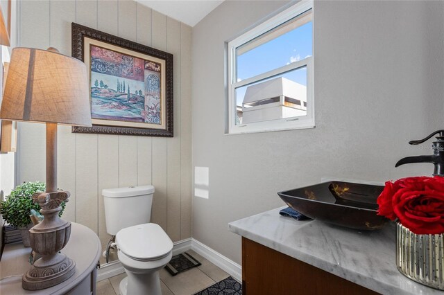 half bath featuring baseboards, toilet, tile patterned flooring, and vanity
