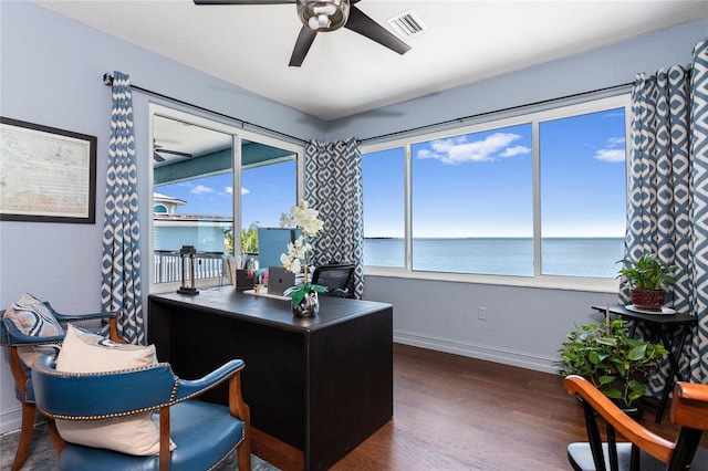 office space with ceiling fan, a water view, visible vents, baseboards, and wood finished floors
