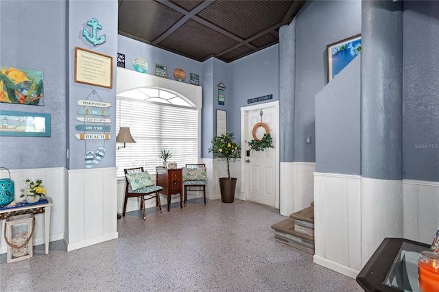 interior space featuring speckled floor, a wainscoted wall, and stairs