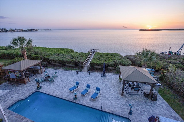 view of swimming pool with a gazebo, a water view, and fence