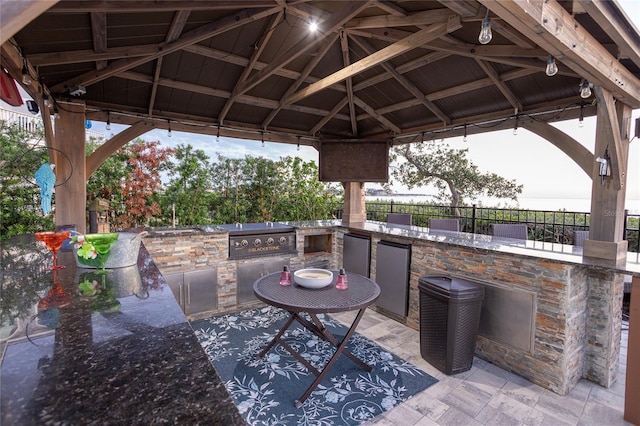 view of patio featuring area for grilling, a gazebo, exterior bar, and fence