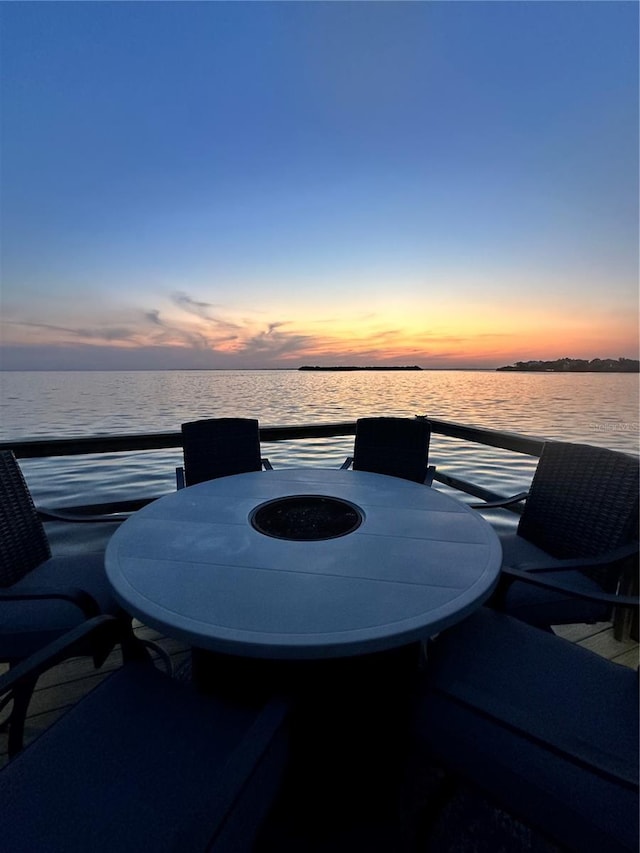patio terrace at dusk with outdoor dining area and a water view