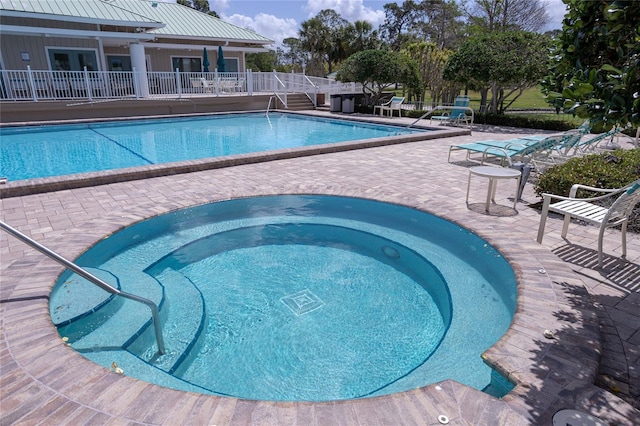 community pool with a patio area and a community hot tub