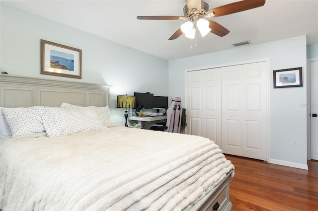 bedroom with a closet, baseboards, a ceiling fan, visible vents, and wood finished floors
