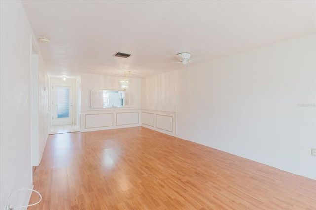 4235 Tamargo Dr Unit 4235, New Port Richey, FL 34652 - empty room with light wood-type flooring, an inviting chandelier, visible vents, wainscoting, and a decorative wall