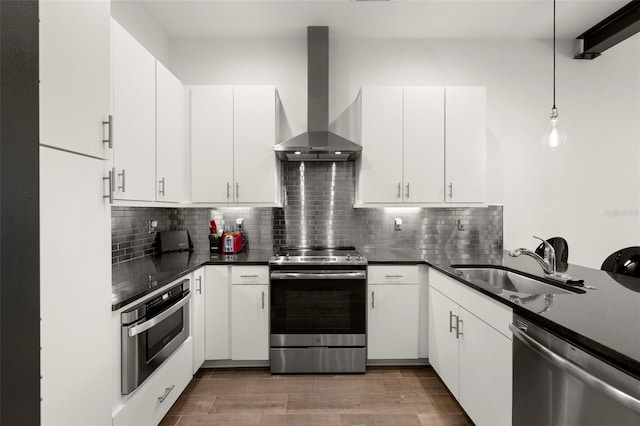 kitchen featuring a sink, tasteful backsplash, appliances with stainless steel finishes, and wall chimney exhaust hood