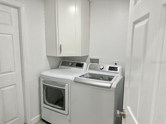 clothes washing area featuring washer and clothes dryer and cabinet space