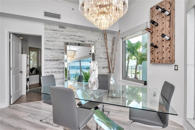 dining space featuring wood finished floors, visible vents, a notable chandelier, and baseboards