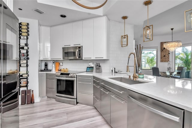kitchen featuring decorative backsplash, a sink, appliances with stainless steel finishes, visible vents, and gray cabinetry