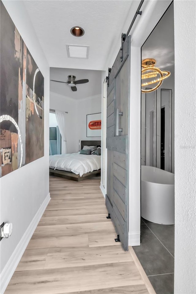 corridor featuring baseboards, a barn door, and wood finished floors
