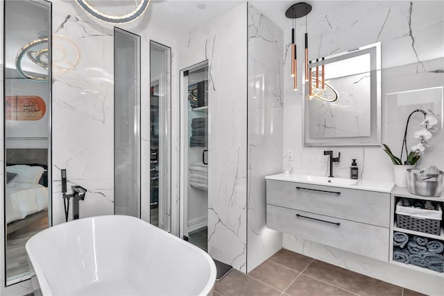ensuite bathroom featuring connected bathroom, tile patterned floors, a soaking tub, and vanity