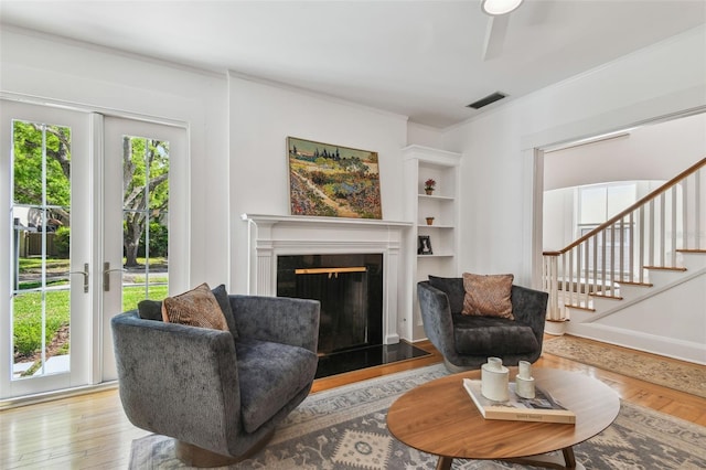 living room with visible vents, plenty of natural light, a glass covered fireplace, and wood finished floors