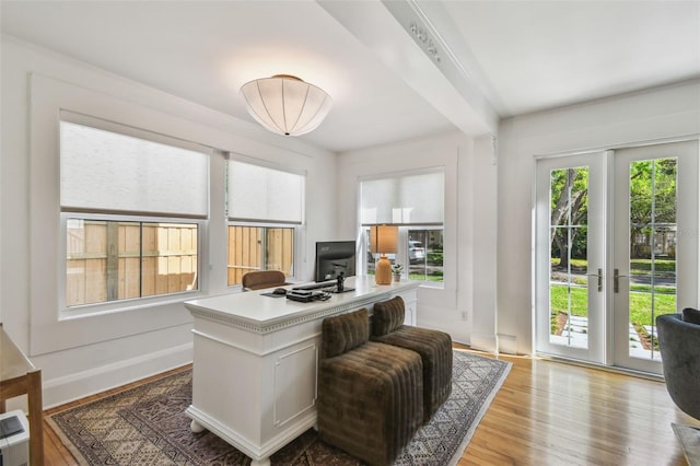 office area with baseboards, beamed ceiling, and wood finished floors