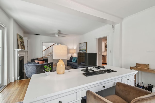 office area featuring a fireplace, light wood finished floors, and a ceiling fan