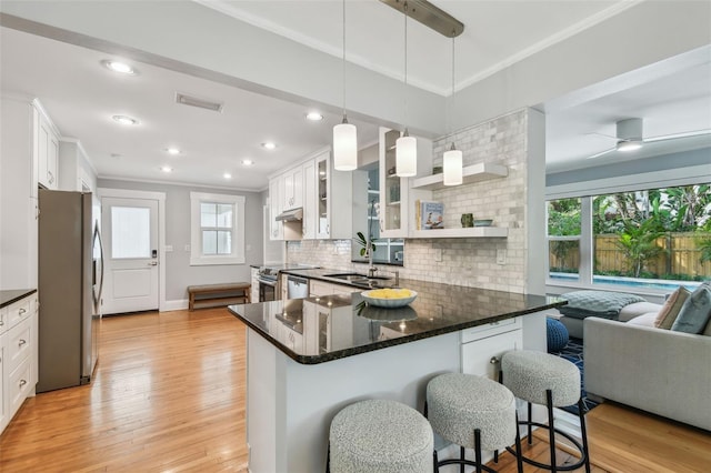 kitchen with ornamental molding, visible vents, a sink, stainless steel appliances, and decorative backsplash